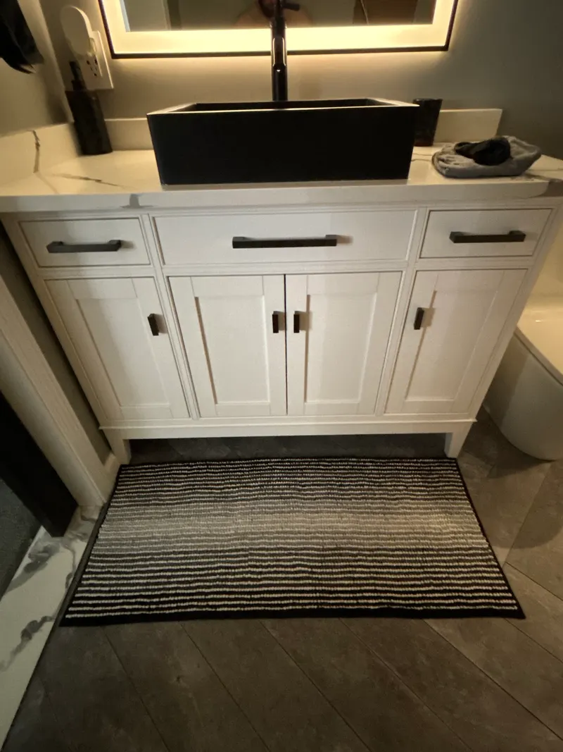 White bathroom vanity with a black vessel sink and a matte black faucet