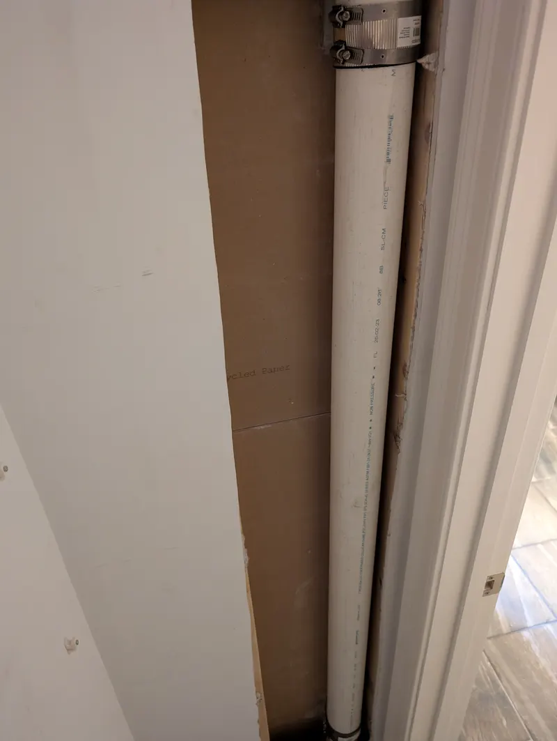 New white PVC drain stack in the same opened wall, joined to the existing pipe with a banded coupling