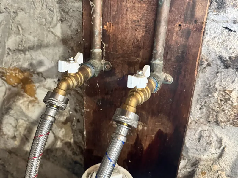 New brass quarter-turn ball valves in the same spot, with the washing machine hoses reconnected