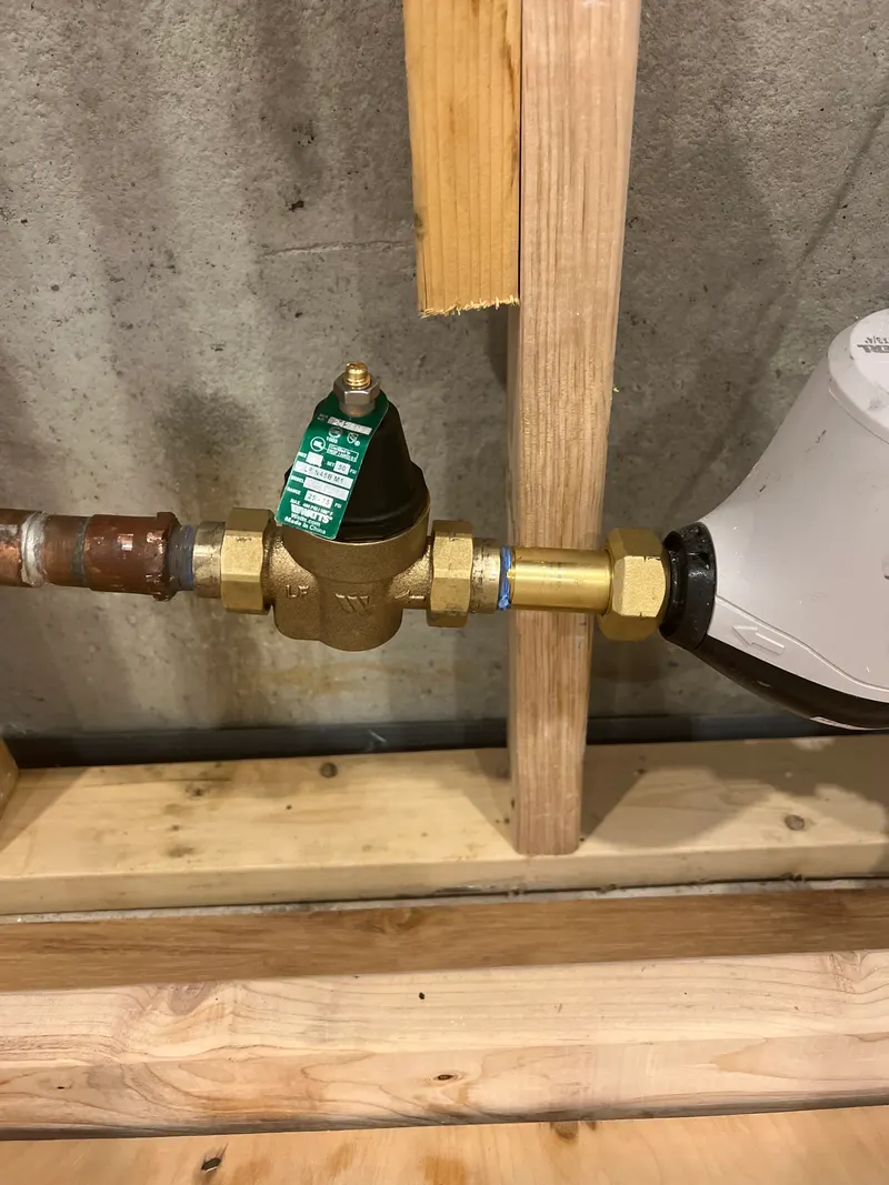 New brass pressure-reducing valve on the main water line beside the water meter