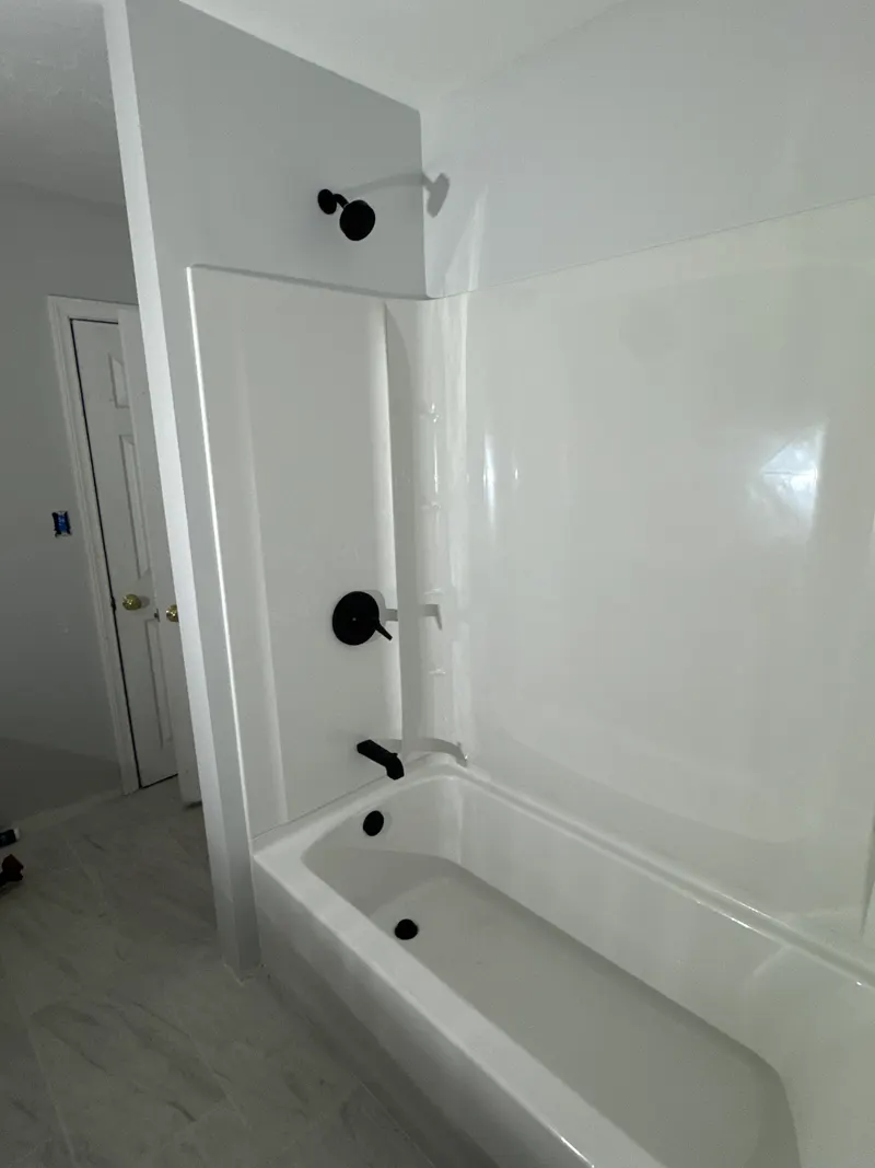 Bathtub with a white surround and a matte black shower head, valve trim and tub spout