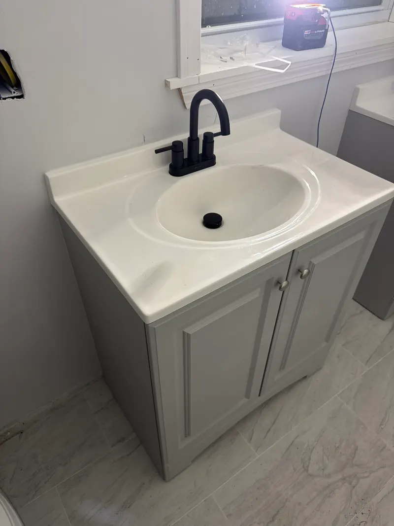 New gray bathroom vanity with a white top and a matte black faucet